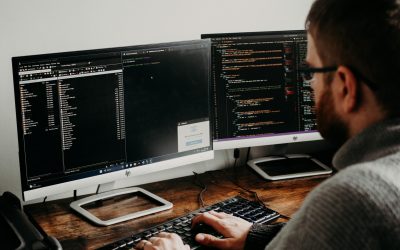 pexels-photo-16129724-16129724 Software developer typing code on dual monitors at a wooden desk.
